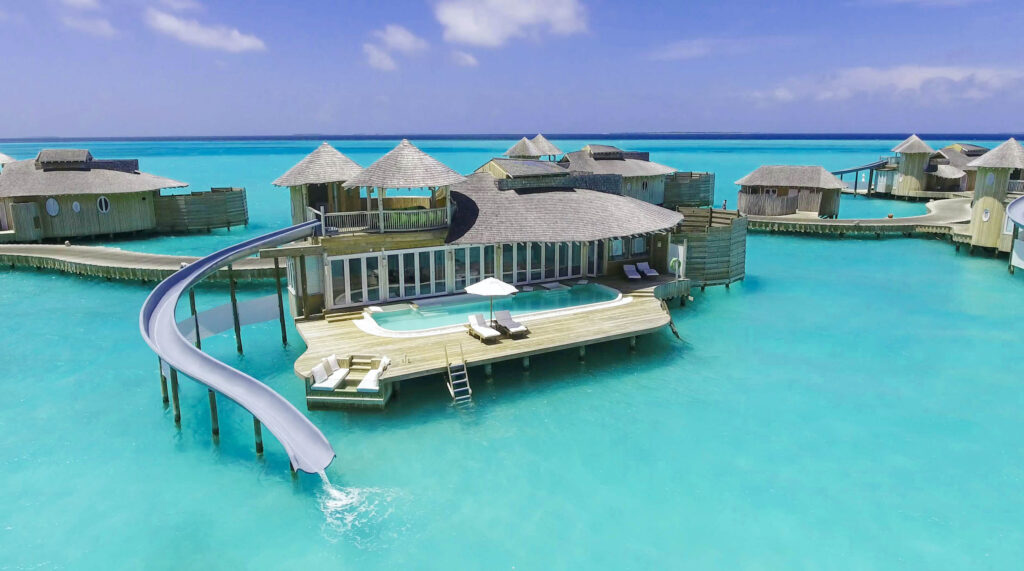 Gruppe von Holz-Wasserbungalows mit Strohdächern über türkisfarbenem Wasser und privatem Pool