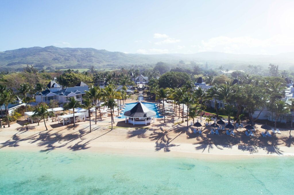Resort Heritage Le Telfair mit großem Pool, weißen Liegen, blauen Dächern und Sandstrand in Mauritius