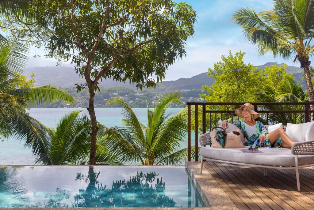 Terrasse mit rundem Sofa, Infinity-Pool, Palmen und Ozean im Hintergrund bei Tageslicht