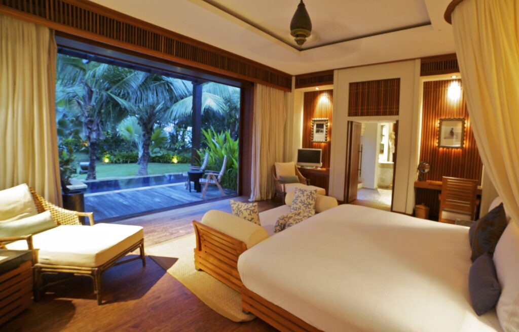 Geräumiges Hotelzimmer mit großem Bett, Chaiselongue, Schreibtisch, Terrasse und Garten mit Palmen