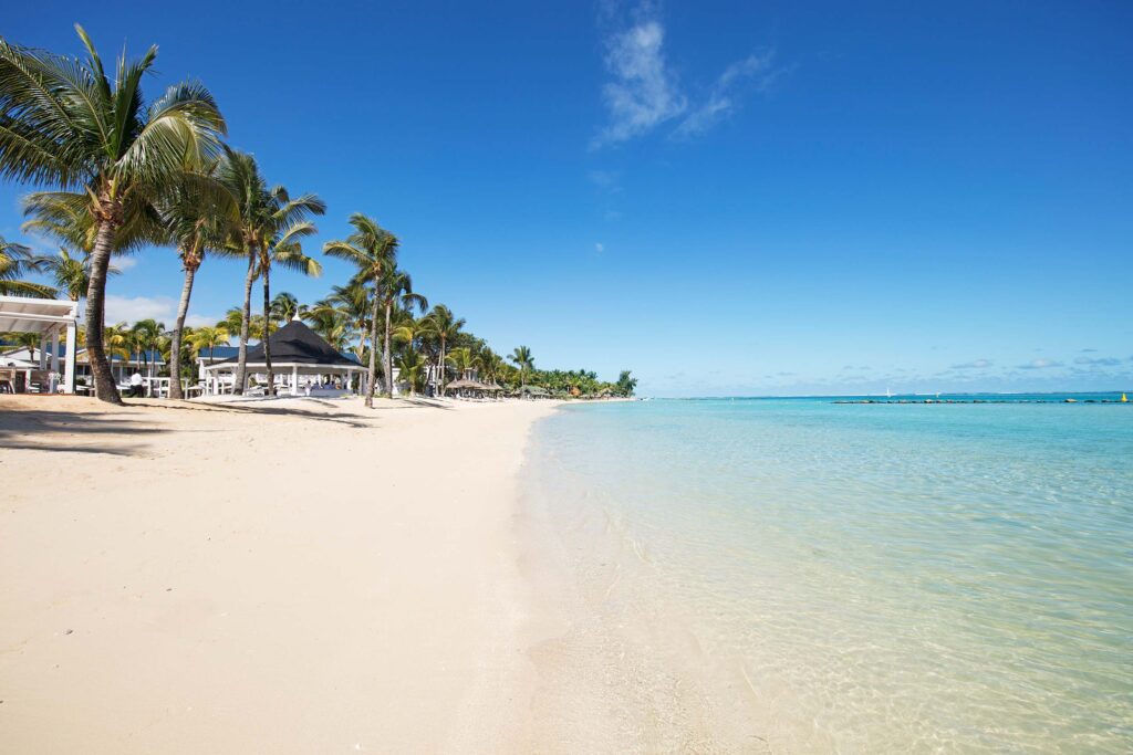 Langer Sandstrand mit Palmen und Pavillons im Hintergrund am Heritage Le Telfair Resort in Mauritius