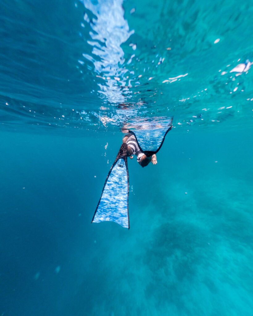 Unterwasseraufnahme eines Schwimmers mit Flossen im blauen Wasser nahe Waldorf Astoria Maldives Ithaafushi