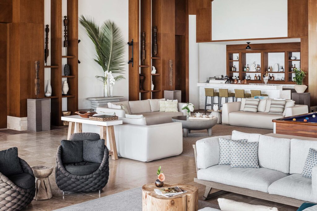 Loungebereich mit Sofas, Stühlen, Holzvertäfelung und Bar im Hintergrund im Waldorf Astoria Maldives