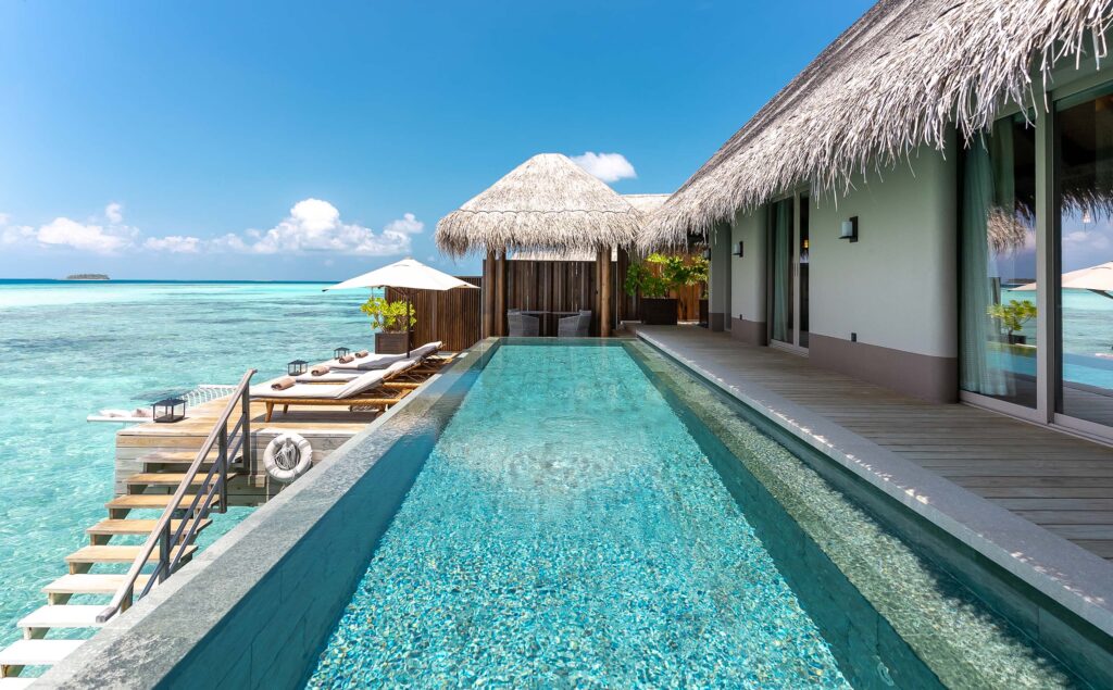 Strandvilla auf den Malediven mit Holzterrasse, privatem Infinity-Pool und Blick auf türkisfarbenes Meer