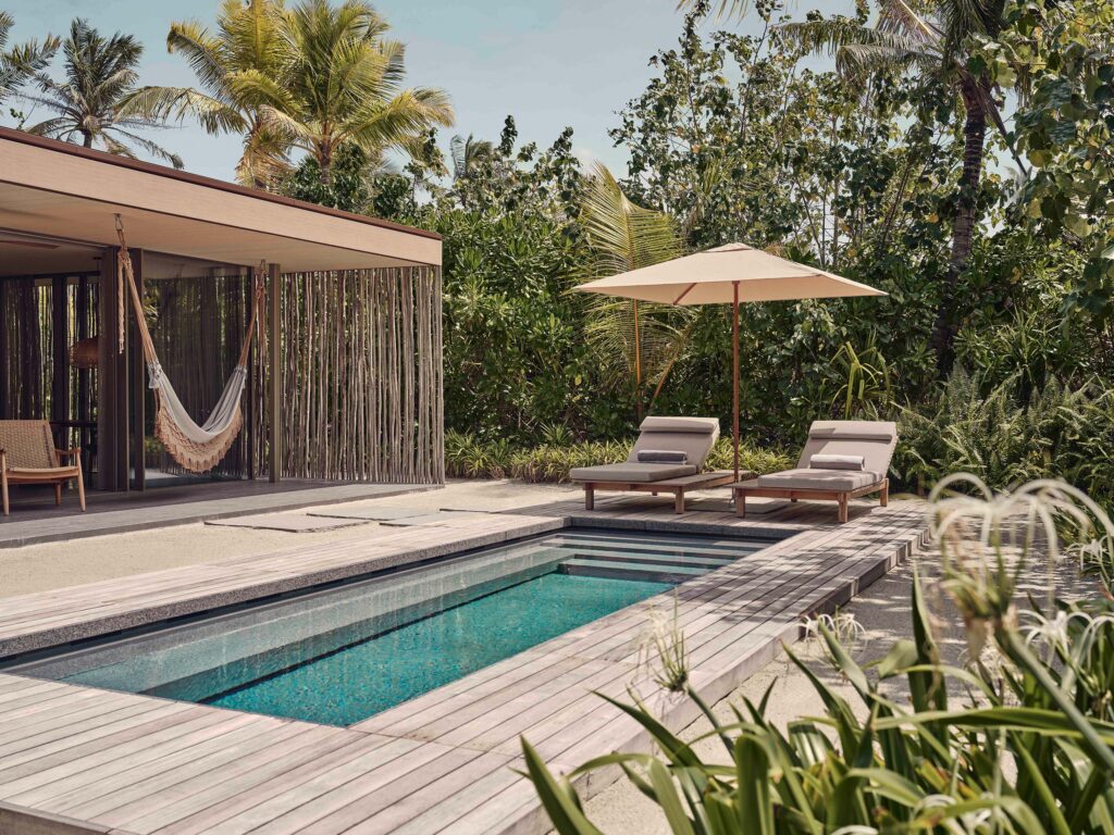 Moderner Außenbereich mit rechteckigem Pool, Holzdecks, zwei Liegestühlen, Sonnenschirm und Hängematte im Hintergrund