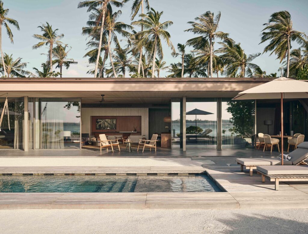 Moderner Poolbereich mit Terrasse, Sonnenliegen und Sonnenschirm, Holz- und Glaselemente, Palmen im Hintergrund