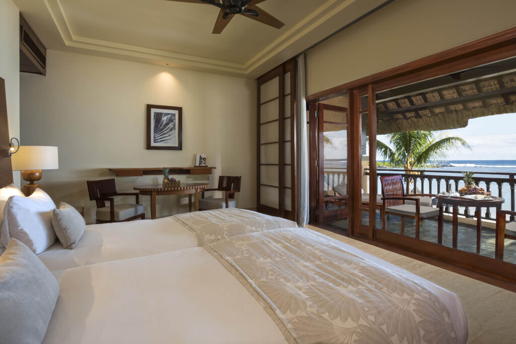 Hotelzimmer mit zwei Einzelbetten, Holzmöbeln, Lampe, Balkon und Meerblick in Mauritius