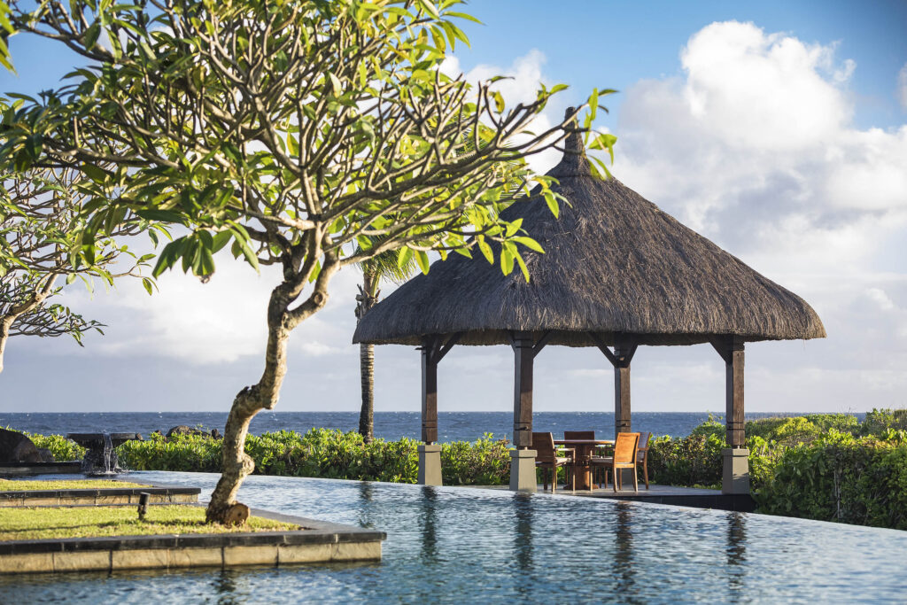 Swimmingpool mit blauen Fliesen und strohgedecktem Pavillon am Meer im Shanti Maurice Resort & Spa