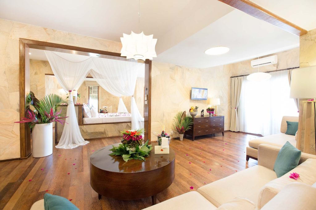 Hotelzimmer mit Holzfußboden, steinverkleideten Wänden, dunklen Holzmöbeln und großen Fenstern in Tulia Zanzibar
