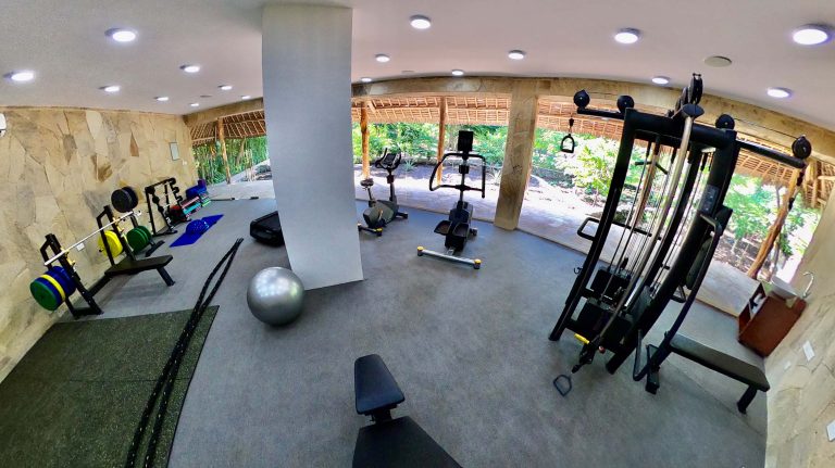 Fitnessraum mit Hantelbänken, Crosstrainer und Fahrradtrainer, Natursteinwände
