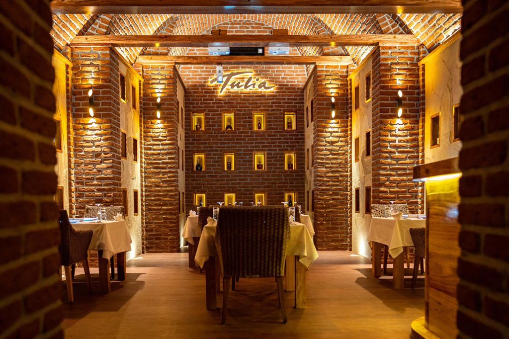 Restaurantbereich mit weißen Tischdecken, geflochtenen Stühlen und roten Backsteinwänden in Tulia Zanzibar