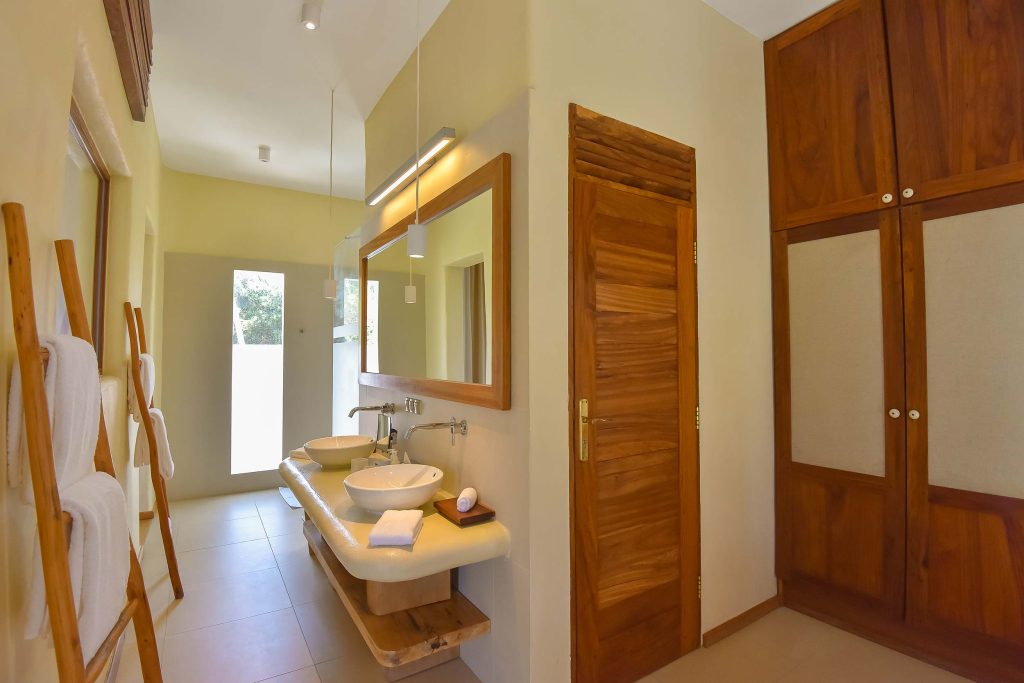 Badezimmer mit zwei weißen Keramikwaschbecken, Holzspiegelrahmen und Kleiderschrank, beiges Wanddesign