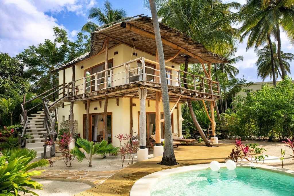 Zweistöckiges Holzgebäude mit Balkon und rundem Pool, umgeben von tropischer Vegetation auf Sansibar