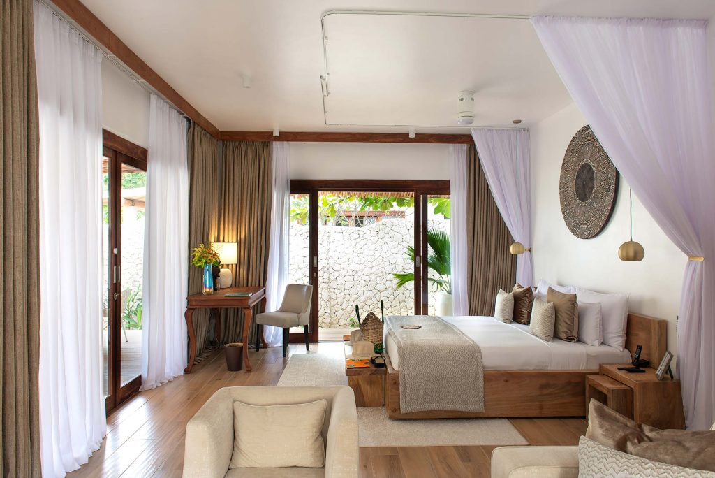Hotelzimmer mit großen Holzfenstern, Baldachinbett mit weißer Bettwäsche, Sitzbereich