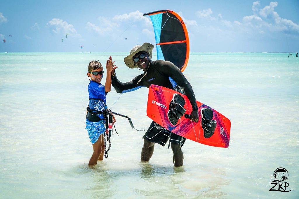 Zwei Personen beim Kitesurfen im flachen Wasser am Strand mit Kiteboards und Trapezen bei hellem Tageslicht