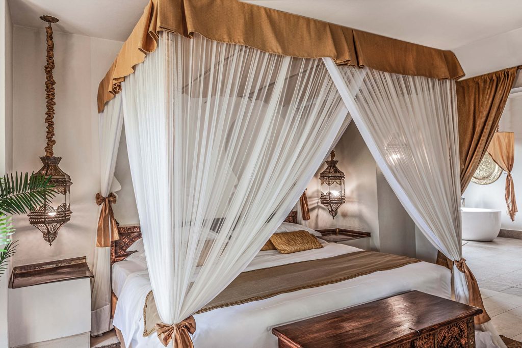 Hotelzimmer mit Himmelbett, weißem Vorhang, goldfarbenem Baldachin und orientalischen Hängelampen
