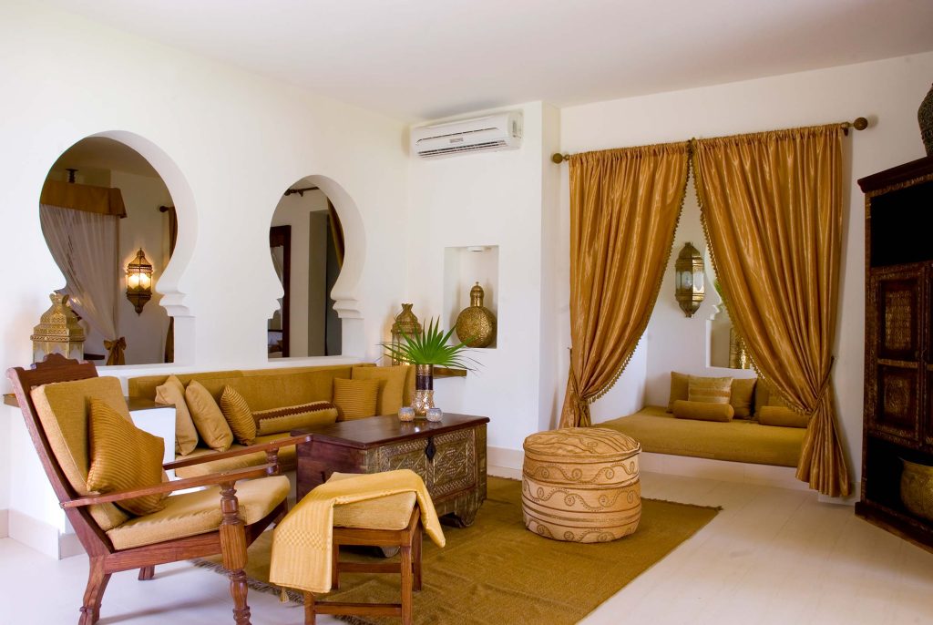 Hotelzimmer im Baraza Resort & Spa mit Holztisch, gepolsterten Bänken und dekorativen Laternen