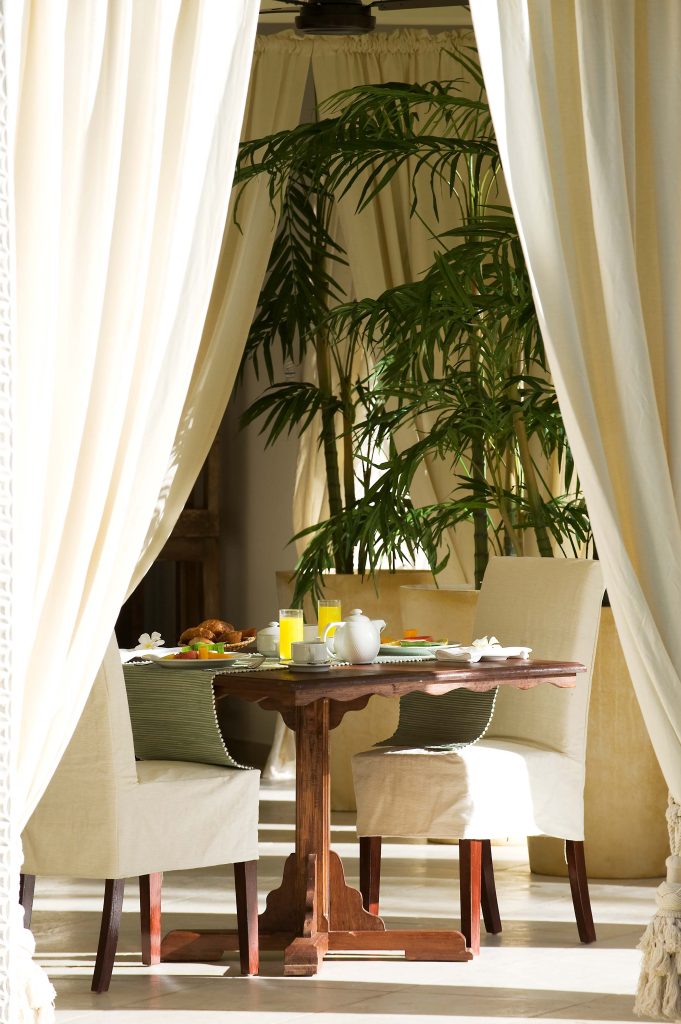 Sitzecke im Restaurant mit Holztisch, weißen Polsterstühlen, Teeservice, Orangensaft