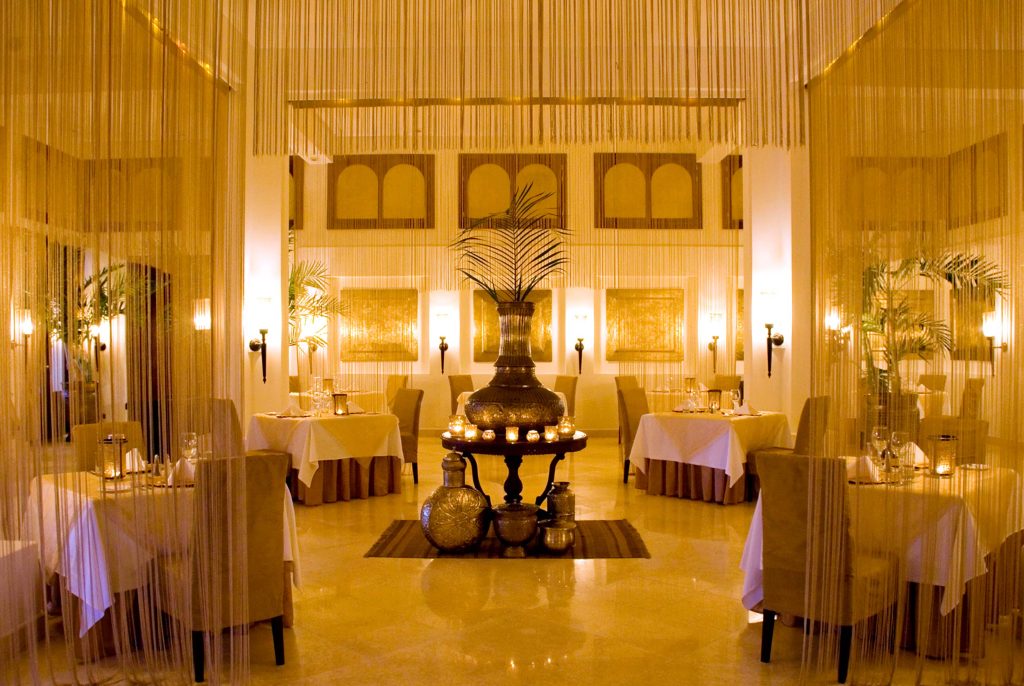Restaurant im Baraza Resort & Spa mit weißen Tischdecken, beigen Stühlen und dekorativer Vase auf dem Tisch