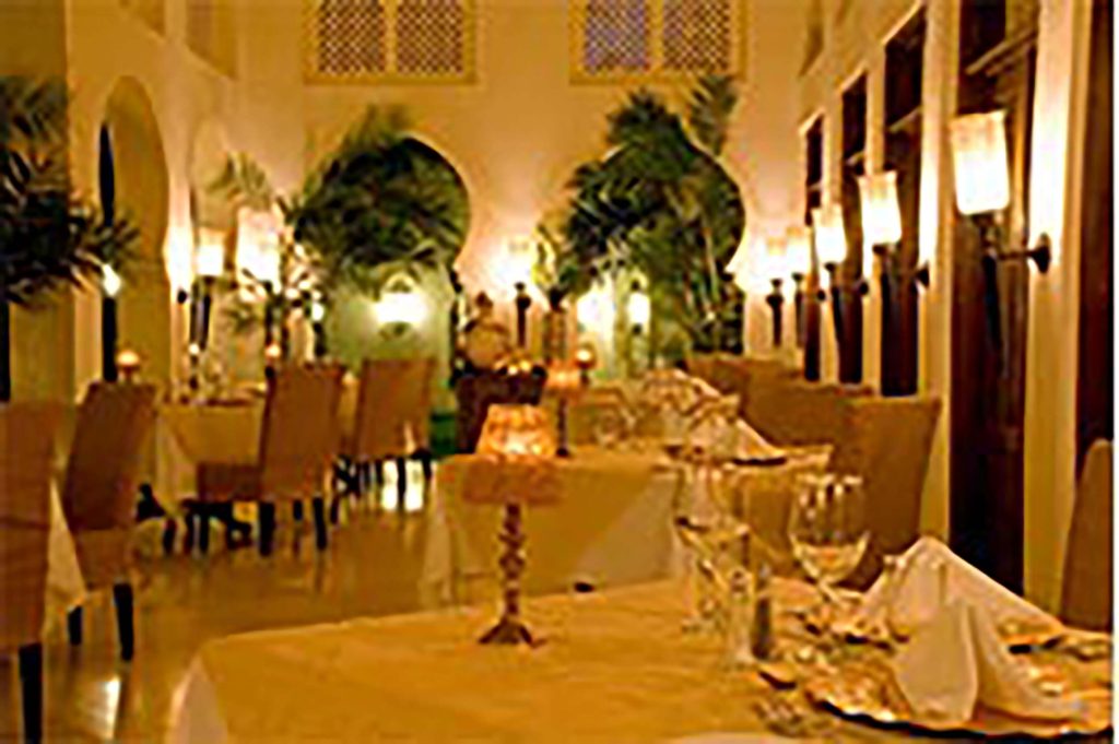 Speisesaal im Baraza Resort & Spa mit weißen Tischdecken, Kristallgläsern und warmem Licht