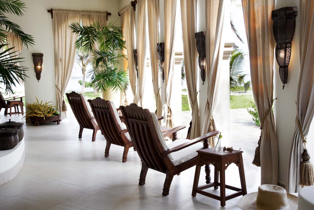 Offener Essbereich mit Holzstühlen, großen Fenstern, hellen Vorhängen und Pflanzen im Baraza Resort & Spa auf Sansibar