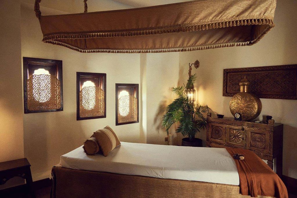 Raum im Baraza Resort & Spa mit breitem Bett, Baldachin, geschnitzten Holzfenstern und dekorativer Kommode
