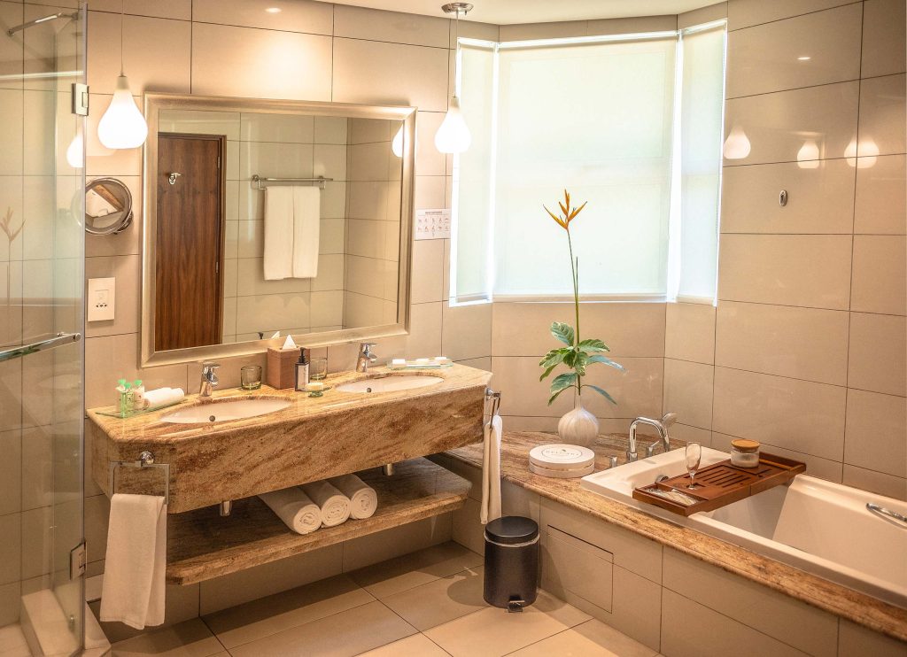 Modernes Badezimmer mit zwei Waschbecken, poliertem Steinwaschtisch, Badewanne und Jalousien