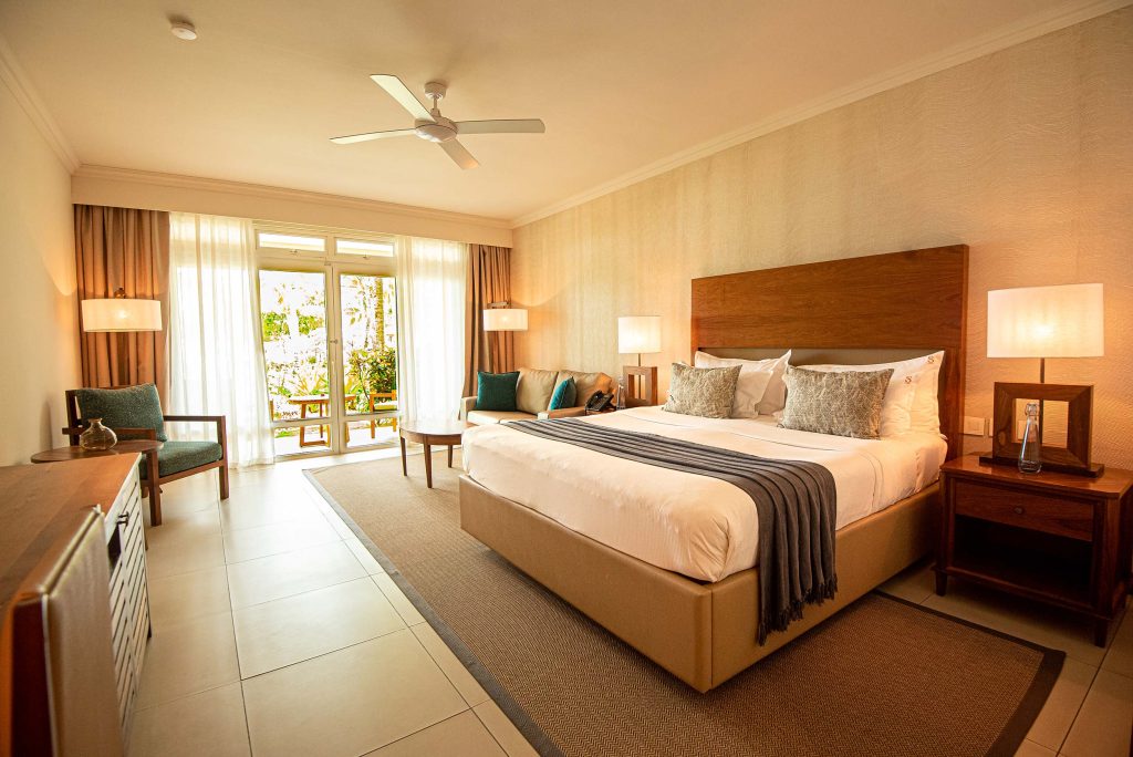Modern eingerichtetes Hotelzimmer mit Doppelbett, Nachttischen, Lampen, Holzkommode und Balkon in Mauritius