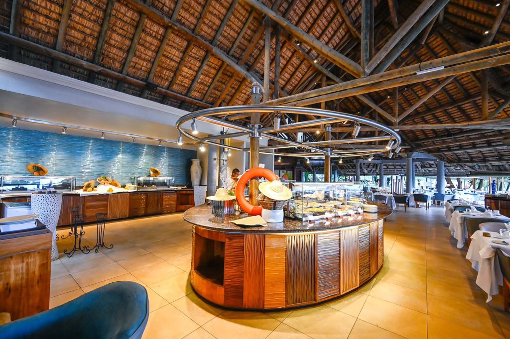 Großer Restaurantbereich mit hoher Holzdecke, rundem Buffet mit Granitplatte und blauen Fliesen an der Wand