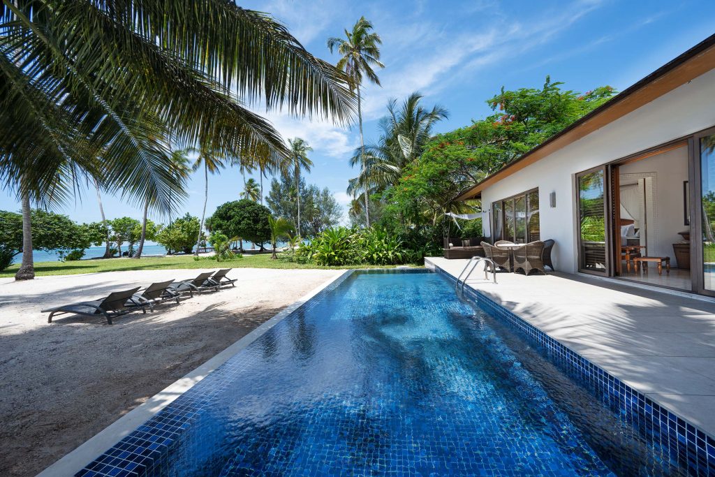 The Residence Zanzibar Außenbereich mit Pool und Terrasse Außenbereich des Hotels The Residence Zanzibar mit rechteckigem Pool, Terrasse mit Rattanmöbeln und Strand im Hintergrund