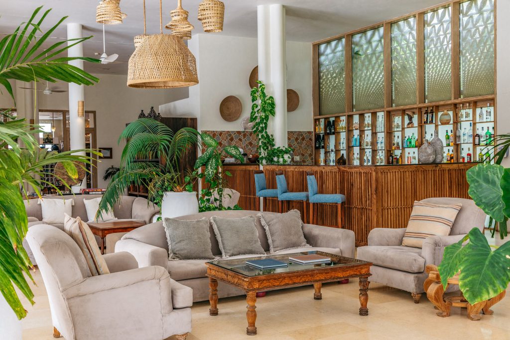 Hotel-Lounge mit beigen Sesseln, hölzernem Couchtisch, Bambusbar und Rattanlampen in Sansibar