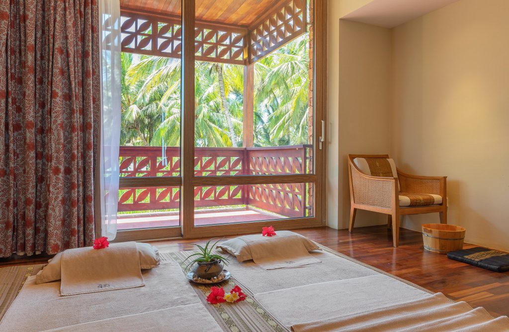 Zimmer mit großer Fensterfront, Balkon mit Holzgeländer und Blick auf Palmen bei Melia Zanzibar