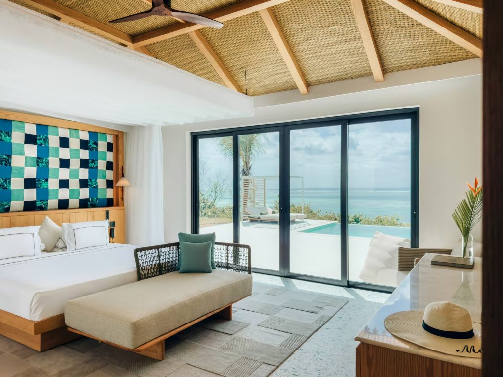 Modernes Hotelzimmer mit großem Bett, Sofa und Meerblick durch hohe Glasfenstertüren in Melia Zanzibar