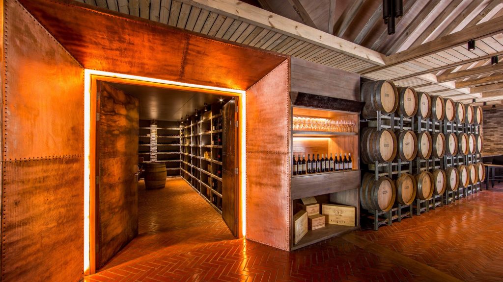 Weinkeller im Amilla Maldives restaurant-cellar-door mit Holzregalen, Weinflaschen und großen Weinfässern