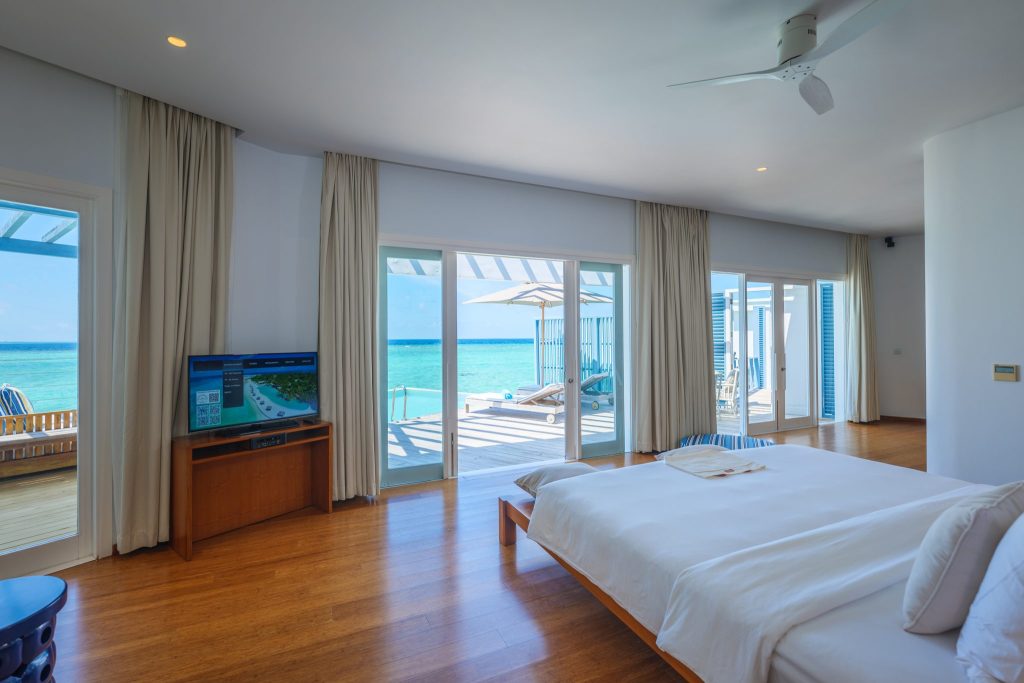 Geräumiges Zimmer im Amilla Maldives mit großem Bett, Holzboden, Flachbildfernseher und Terrasse mit Meerblick