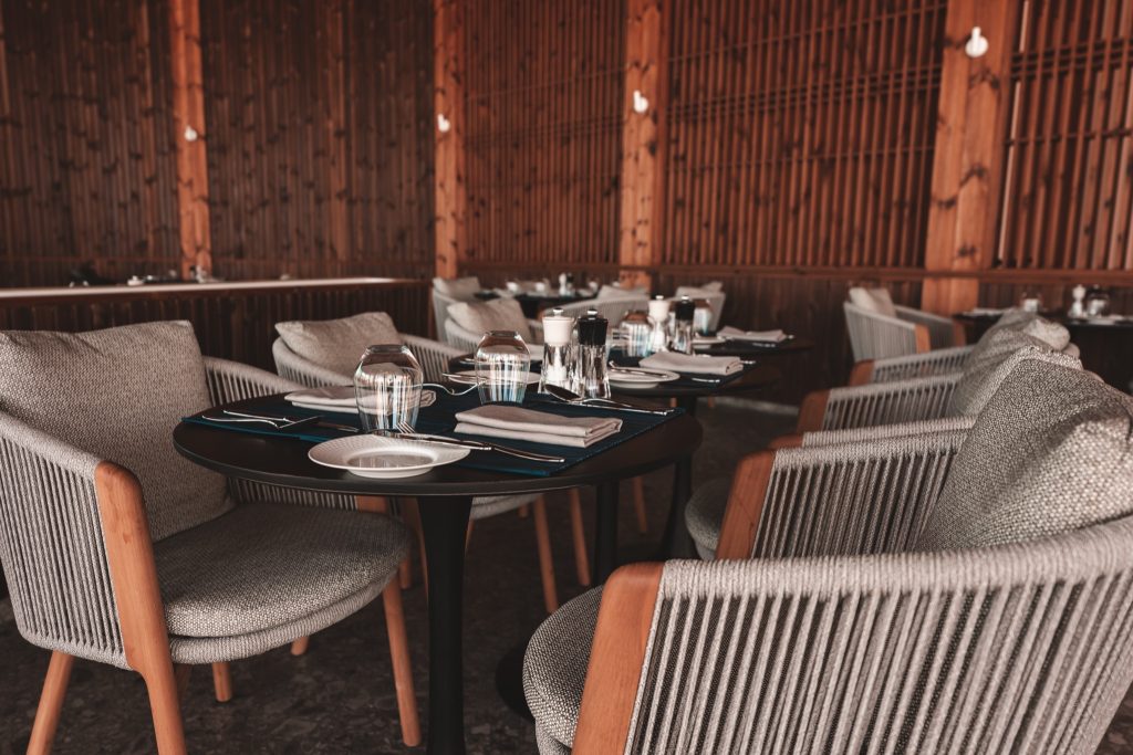 Innenbereich des ananea Madivaru Maldives Restaurants mit gedeckten Tischen, grauen Polstersesseln