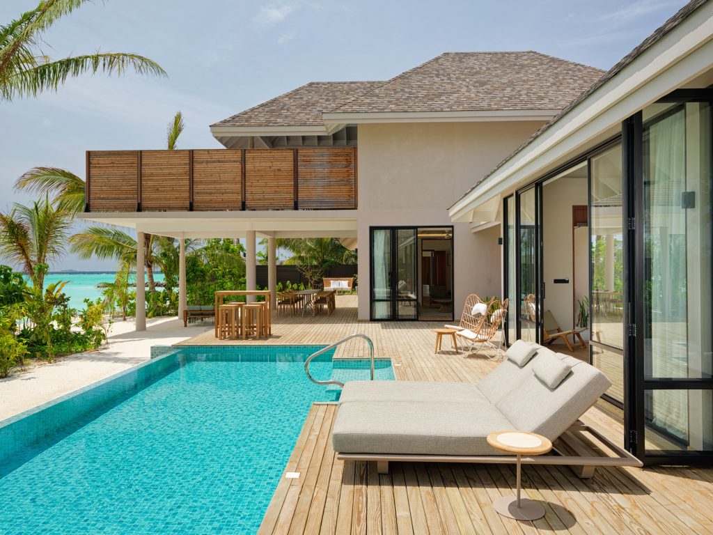Außenbereich ananea Madivaru Maldives mit blauem Pool, Holzterrasse und verputzten Wänden bei Tageslicht