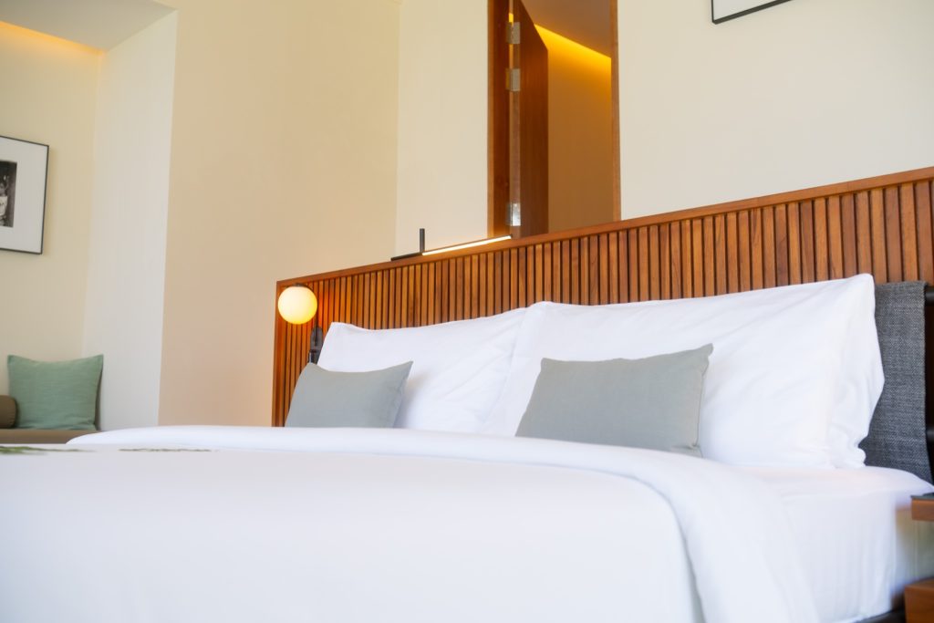 Hotelzimmer ananea Madivaru Maldives mit weißer Bettwäsche, grauen Kissen und hellem Holz-Kopfteil
