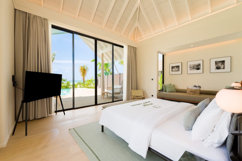 Hotelzimmer mit großem Bett, Flachbildfernseher und Terrasse mit Rattanmöbeln auf den