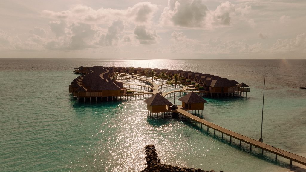 Deluxe Water Pool Villa auf Stelzen mit Holzhütten und strohgedeckten Dächern über türkisfarbenem Wasser