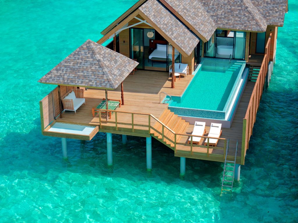 deluxe water pool villa mit Holzterrasse, privatem Pool und Liegestühlen über türkisfarbenem Wasser