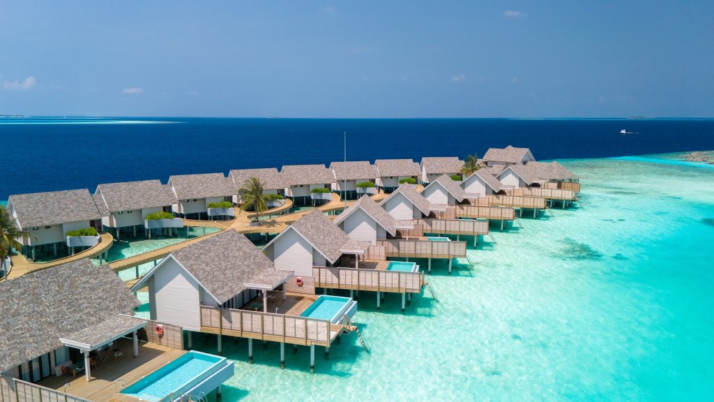Wasserbungalows mit grauen Schindeldächern und weißen Wänden auf Pfählen über türkisfarbenem Wasser mit privaten Pools