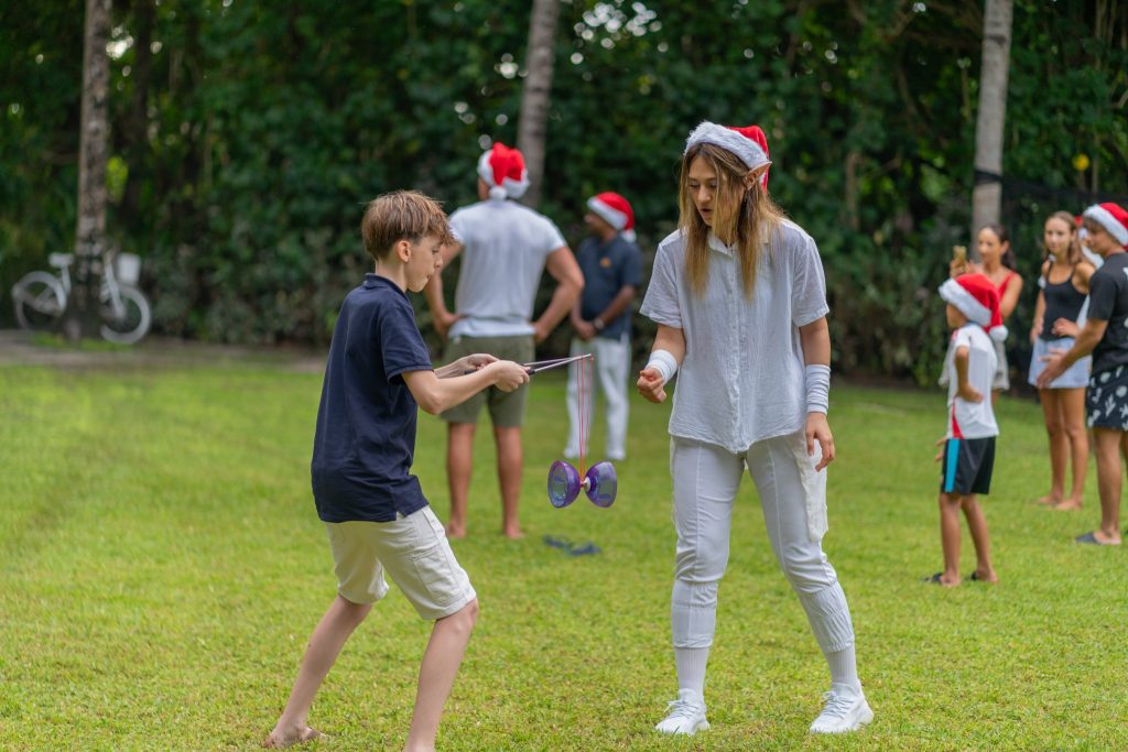 Gruppe von Menschen auf grüner Wiese mit Diabolo-Spielzeug und Weihnachtsmützen bei Tageslicht