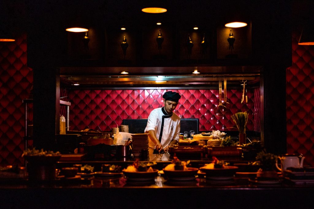 Koch arbeitet in der Restaurant Kai Küche bei Ayada Maldives vor roter gepolsterter Wand mit Küchenutensilien