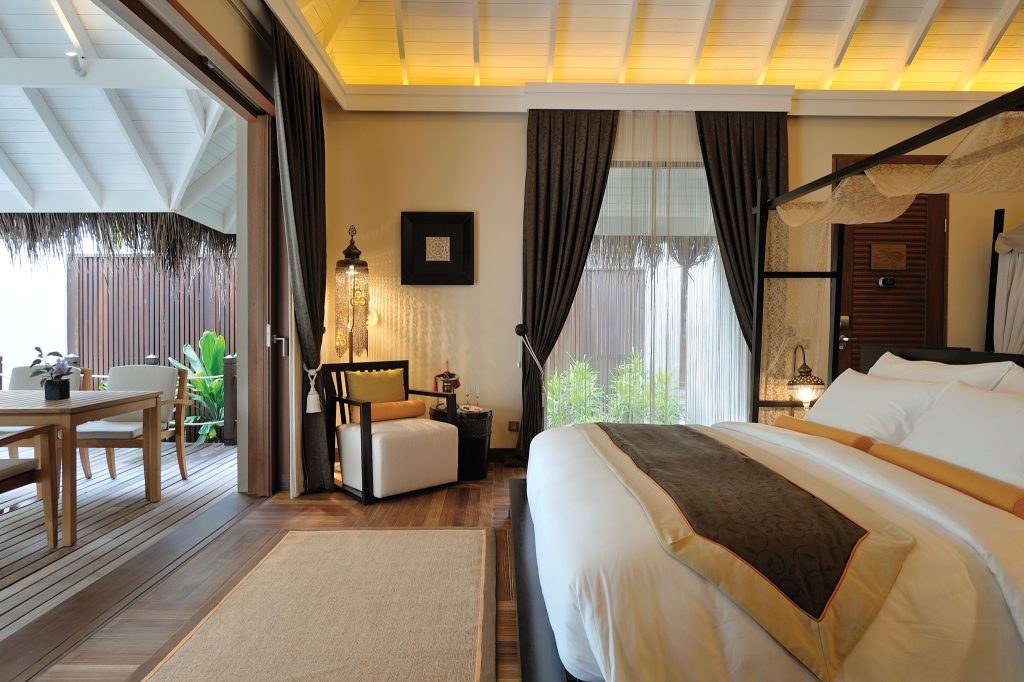 Zimmer der Ayada Maldives Beach Family Suite mit großem Bett, Sessel, Balkon