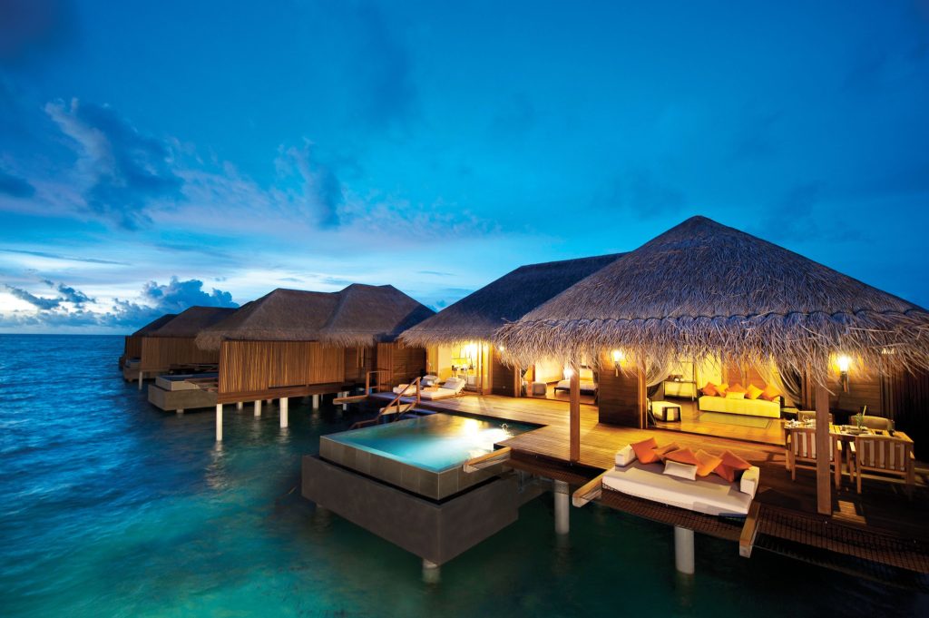 Überwasserbungalows mit Holzterrassen und kleinem Pool bei Sonnenuntergang auf den