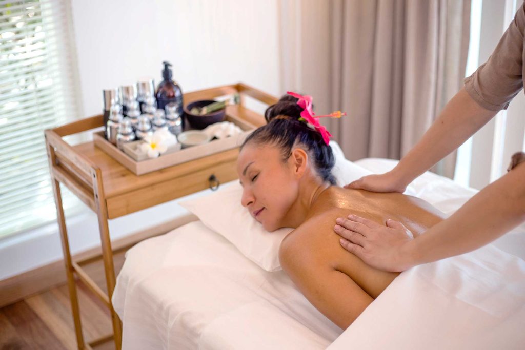 Massageraum im Baglioni Resort Maldives mit weißem Massagetisch, Holzwagen und weichem Tageslicht durch Lamellenjalousien