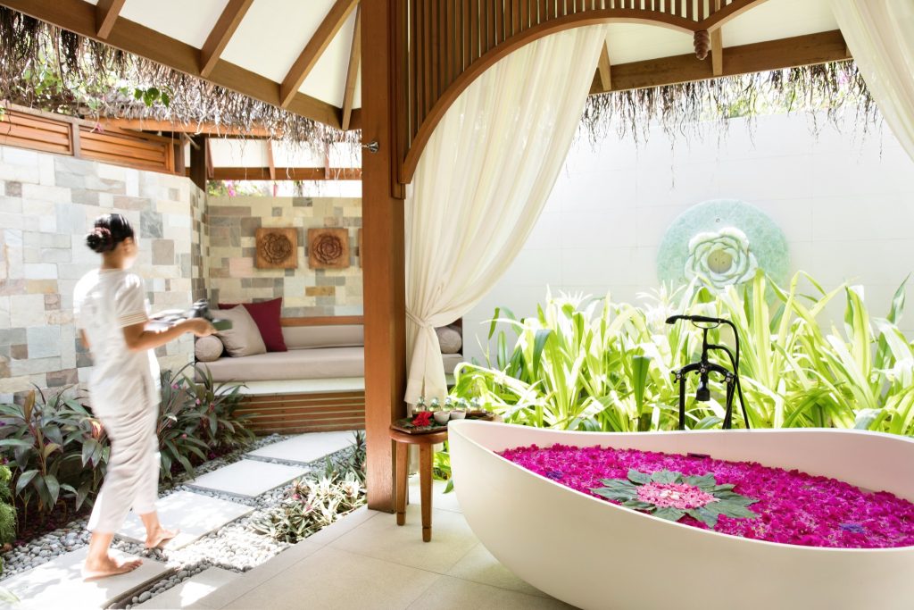 Außenbereich im Baros Maldives Serenity Spa mit freistehender Badewanne, Natursteinwand und Holzüberdachung