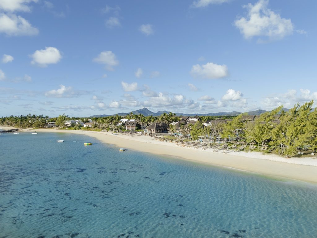 Luftaufnahme des C Mauritius Strandes mit klarem türkisblauem Wasser, hellem Sand und Resortgebäuden im Hintergrund