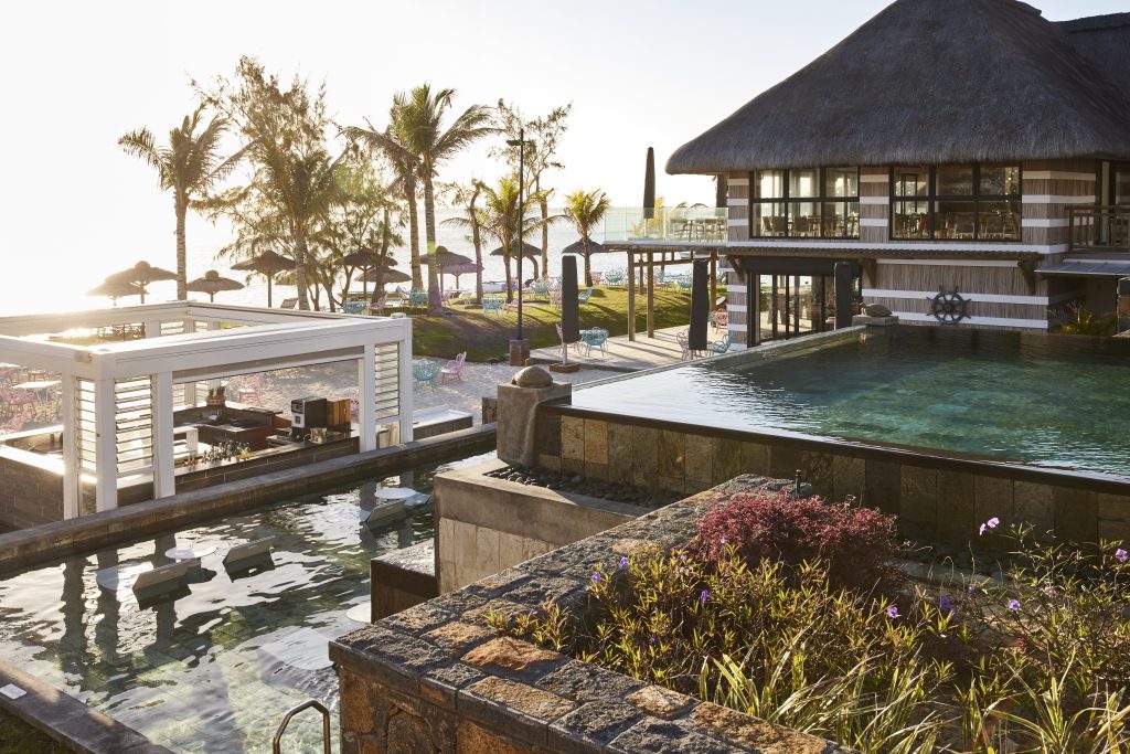 Offener Bereich des C Mauritius Beach Bistro mit Pool, reetgedecktem Gebäude, Bar und tropischer Umgebung